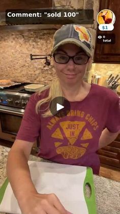 a woman is making pizza in the kitchen with her hands on top of an unwrapped sheet of paper