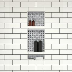 two black and white shelves on the side of a brick wall with bottles in them