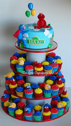 a three tiered cake with cupcakes on it