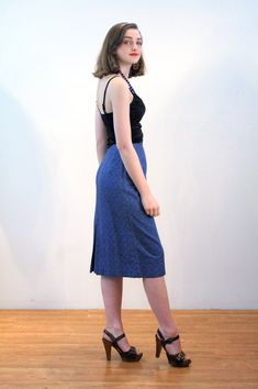 This is a classic vintage 1960s blue paisley print pencil skirt. It features vertical pleats below the waistband, a center walking vent in the back, and a hem that ends just below the knee. It has a stylized, subtle floral paisley pattern, in turquoise green and navy blue on a deep blue background. The fabric is a sturdy cotton with a satin lining inside at the waist. The skirt closes with a button at the left hip and a 6 inch metal side zipper that is expertly placed, so that it is completely h Vintage Fitted Midi Skirt, Retro Blue Party Skirt, Vintage Blue Skirt, Fitted Vintage Blue Skirt, Retro Blue Knee-length Skirt, Vintage Blue Fitted Bottoms, Vintage Fitted Blue Bottoms, Vintage Blue Knee-length Skirt, Fitted Vintage Blue Bottoms