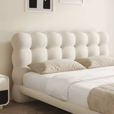 a white bed sitting in a bedroom next to two pictures