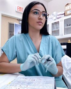 a woman in scrubs and gloves sitting at a table