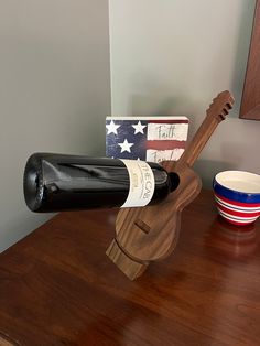 a wooden wine bottle holder sitting on top of a table next to a bowl and an american flag