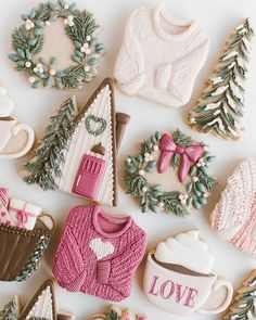 decorated cookies are laid out on a white surface, including sweaters and mittens