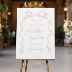 an easel with a wedding sign on it in the middle of a room filled with tables and chairs