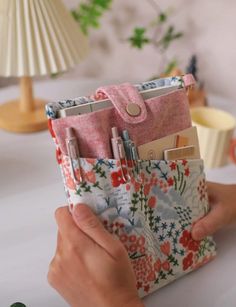 a person holding a purse with pens and pencils in it while sitting at a table