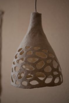 a hanging light made out of clay with holes in the middle and an attached cord