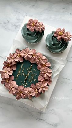 two cupcakes decorated with pink flowers on top of a green plate and white paper