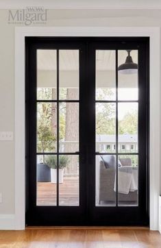 an empty room with black doors and wood floors