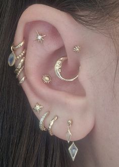 a woman wearing ear piercings with stars, moon and sun designs on her ears