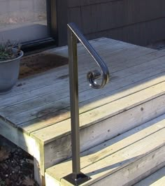 a metal hand rail sitting on top of a wooden deck next to a potted plant