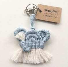 a crocheted elephant keychain with tassels and a tag attached to it