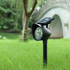 a solar powered light in the grass near a bridge