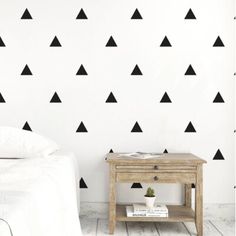 a white bed sitting next to a wall with black triangle decals on the walls