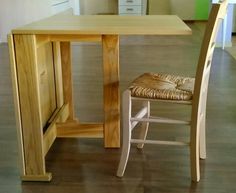 a wooden table with two chairs next to it on the floor in front of a kitchen