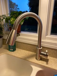 a kitchen sink with a faucet next to a window and potted plant