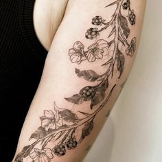 a woman's arm with flowers and leaves on it