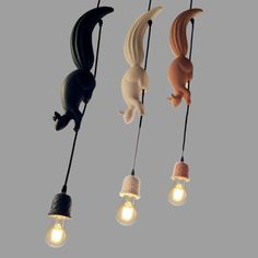 three light bulbs are hanging from the ceiling and one is shaped like an animal, while the other has a cat on it's tail