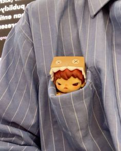 a small toy in the pocket of a man's blue striped dress shirt and tie