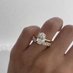 a woman's hand with a diamond ring on top of her finger and an engagement band