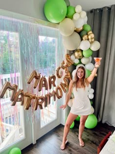 a woman standing in front of balloons and streamers with the words happy birthday on it