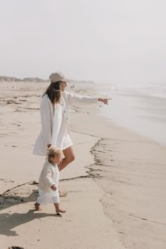 a woman and child on the beach pointing at something