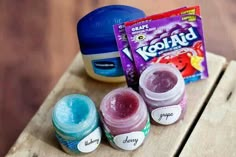 three jars of toothpaste sitting on top of a wooden table next to a packet of kohl aid