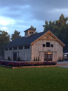 a barn with flowers in the front yard