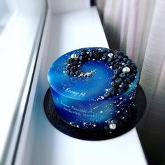 a blue cake sitting on top of a white counter next to a window sill