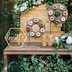 donuts are displayed on top of a wooden table with greenery and white flowers