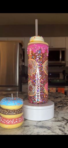 two donuts sitting on top of a counter next to a cup with a straw in it