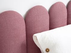 a close up of a pillow on a bed with pink headboard and white pillows