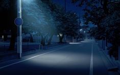 an empty street at night with the lights on and trees in the foreground,