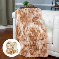 a brown and white fur blanket sitting on top of a couch next to a potted plant