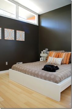 a bed sitting on top of a hard wood floor next to a wall with three paintings