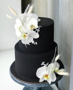 a black cake with white flowers and feathers