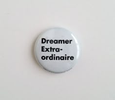 a white button with black text that says,'dreamer extra - ordinaire '