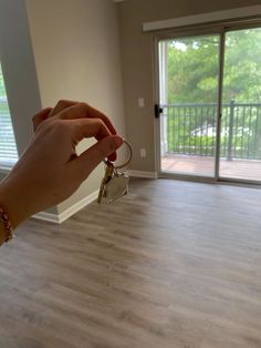 a person holding two keys in front of a sliding glass door that leads to a balcony