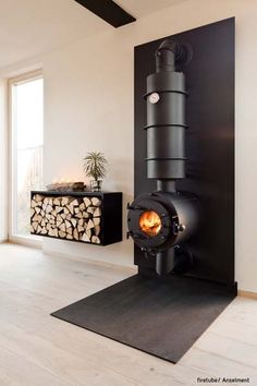 a wood burning stove in a living room next to a firewood log holder and window