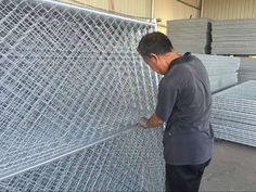 a man standing next to a large pile of metal wire mesh fencing in a warehouse