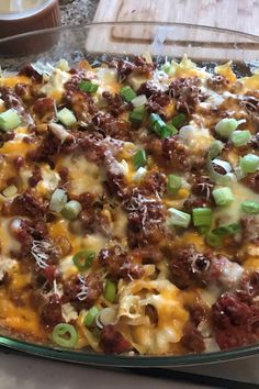 a casserole dish with meat, cheese and green onions in it on a table