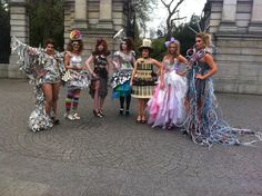 a group of women standing next to each other in front of a stone building wearing costumes