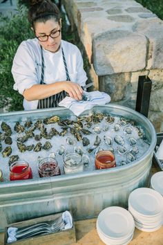 a man standing in front of a large metal pan filled with oysters and sauces