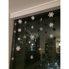 snowflakes hanging from the window in front of a cityscape at night