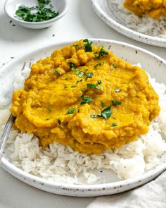 two plates filled with rice and curry on top of each other next to a fork