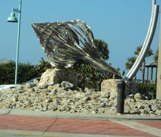 a metal sculpture sitting on top of a pile of rocks next to a street light