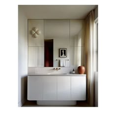 a bathroom with a sink, mirror and vase on the counter in front of it