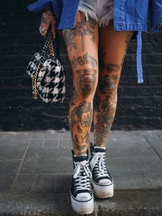 a person with tattoos on their legs holding a handbag