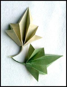 an origami bird next to a green leaf