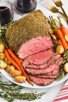 roast beef with carrots, potatoes and rosemary sprigs on a white plate